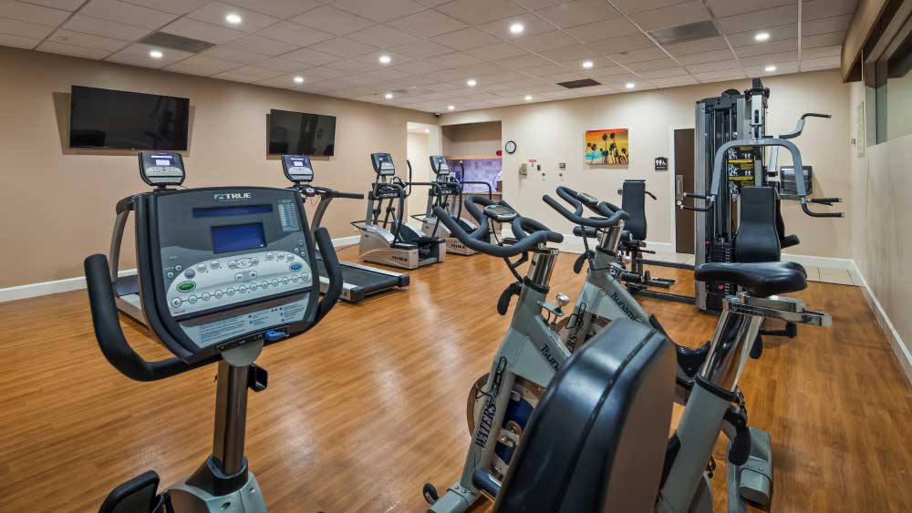 Excercise Room displaying stationary bikes, treadmills, flatscreen tvs weights machine complimentary towels