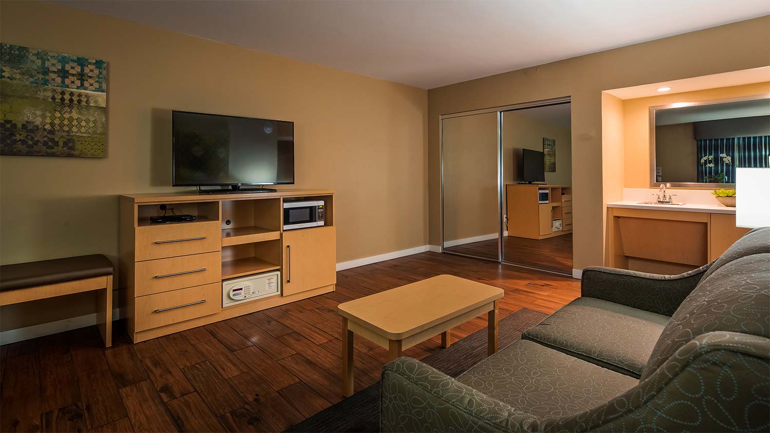 Room displaying TV safe microwave and refrigerator a mirrored closet sofa and sink